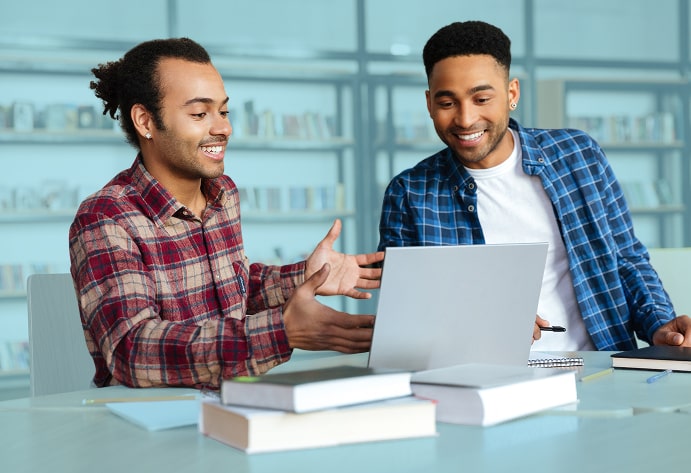 Two men smiling in a meeting looking at a notebook