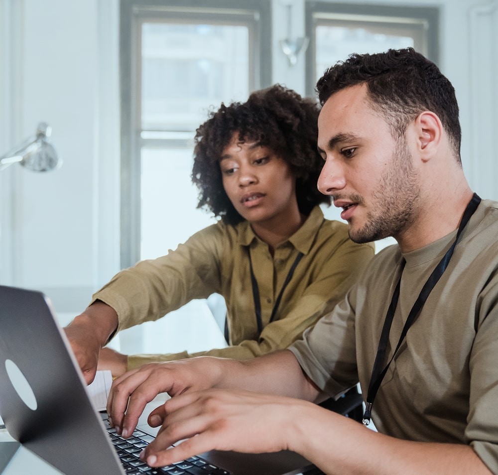 Man and woman in a face-to-face meeting where the man is typing and the woman is pointing at the laptop screen