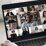 Notebook with the screen of an online meeting showing the faces of several people