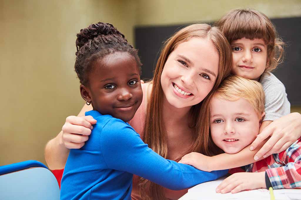 Children hug their kindergarten teacher